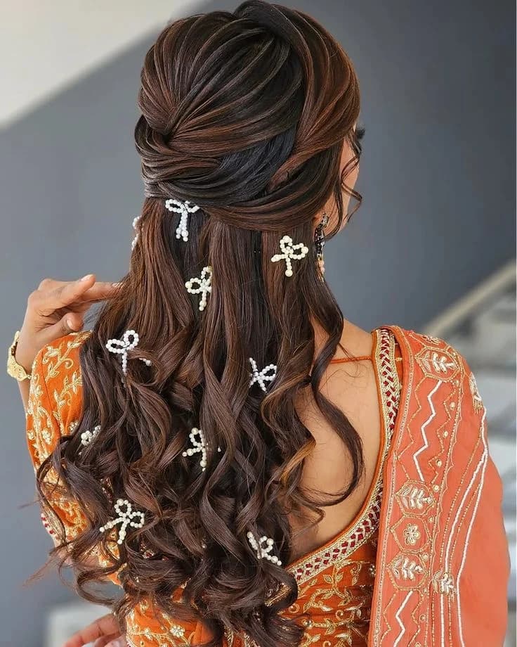 Half-up style with pearl bow pins set through long waves, worn with an orange outfit