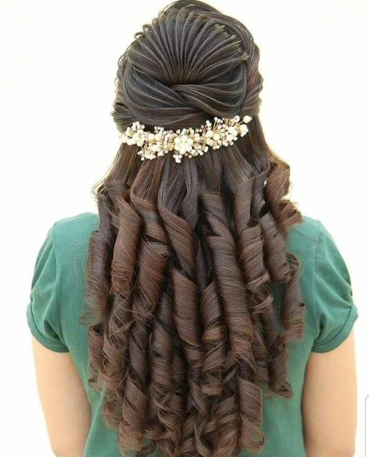 Half-up style with a pearl hairband above tight ringlet curls