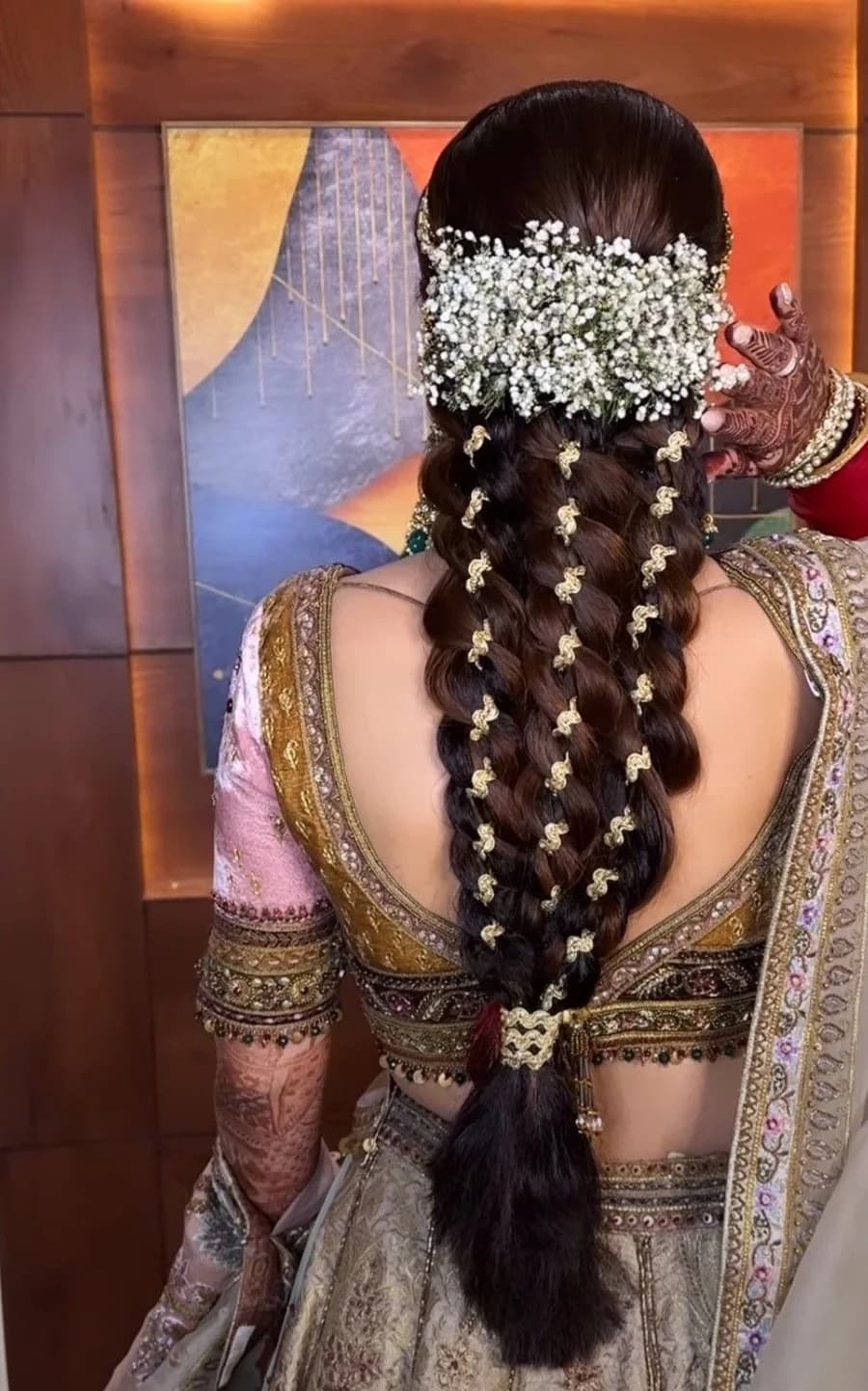 Wide bridal braid with a baby’s breath crown and gold braid ornaments worked down the plait