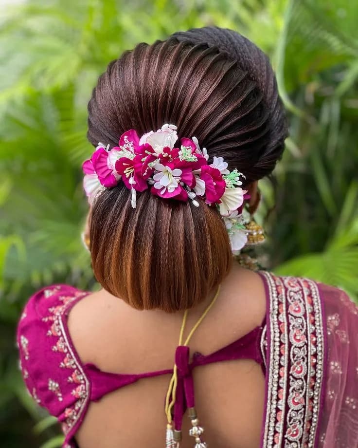Sleek low bun dressed with magenta and white flowers, worn with a magenta lehenga