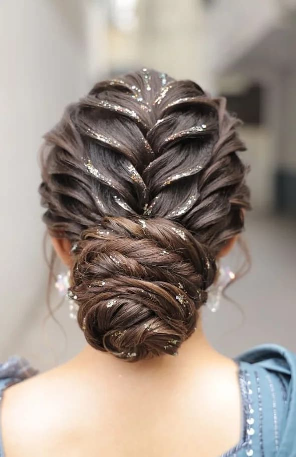 Braided updo with glitter worked through the plait, coiled into a low bun