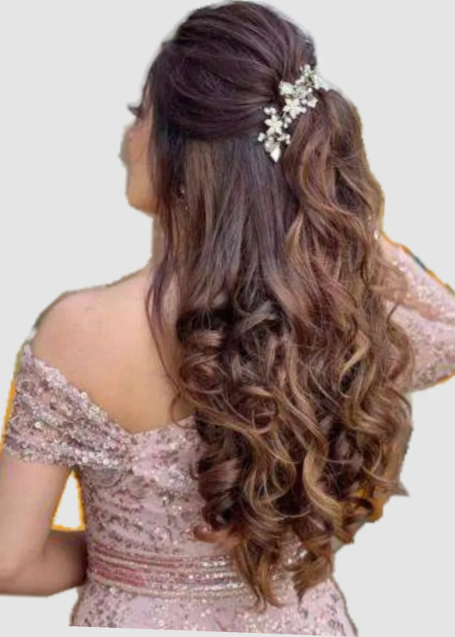 Half-up style with a floral clip and full curls, worn with a blush embroidered outfit