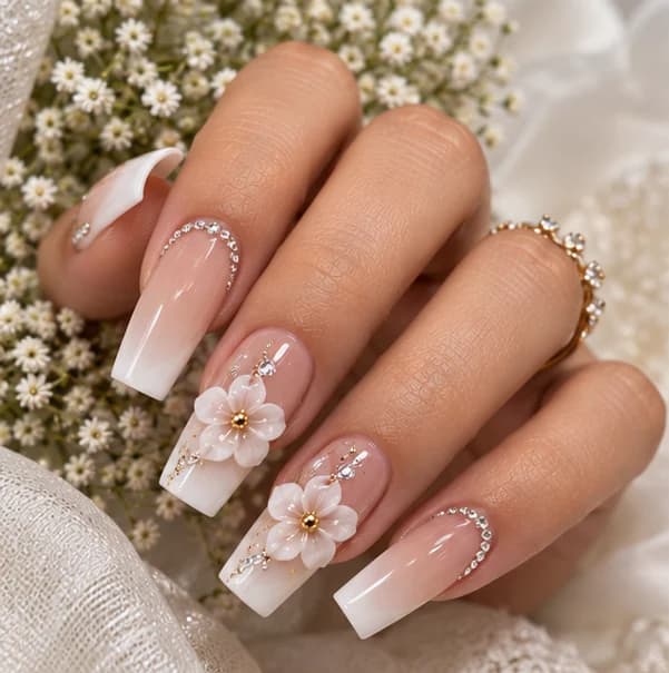 White and nude ombre coffin nails with three-dimensional flowers and crystal cuticle accents