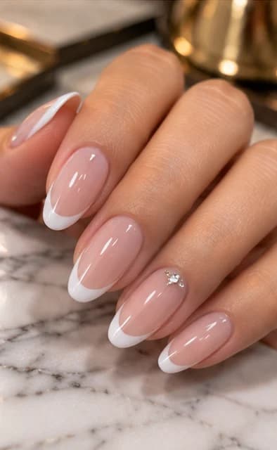 Classic white French almond gel nails with a single crystal accent