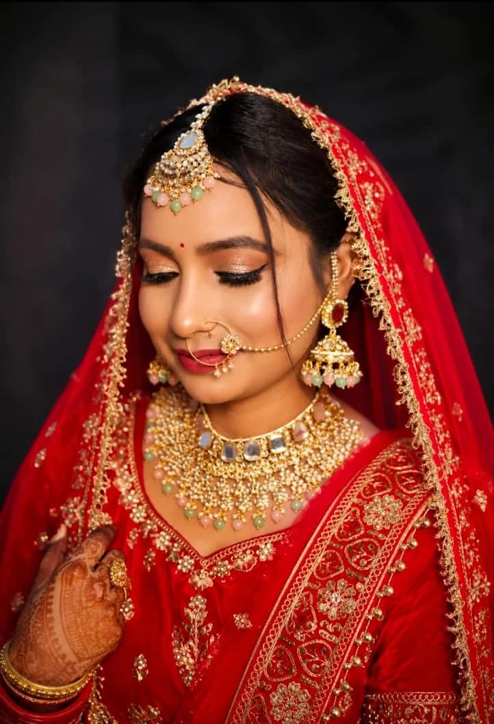 Red bridal look with a gold shimmer eye, kundan choker and full henna