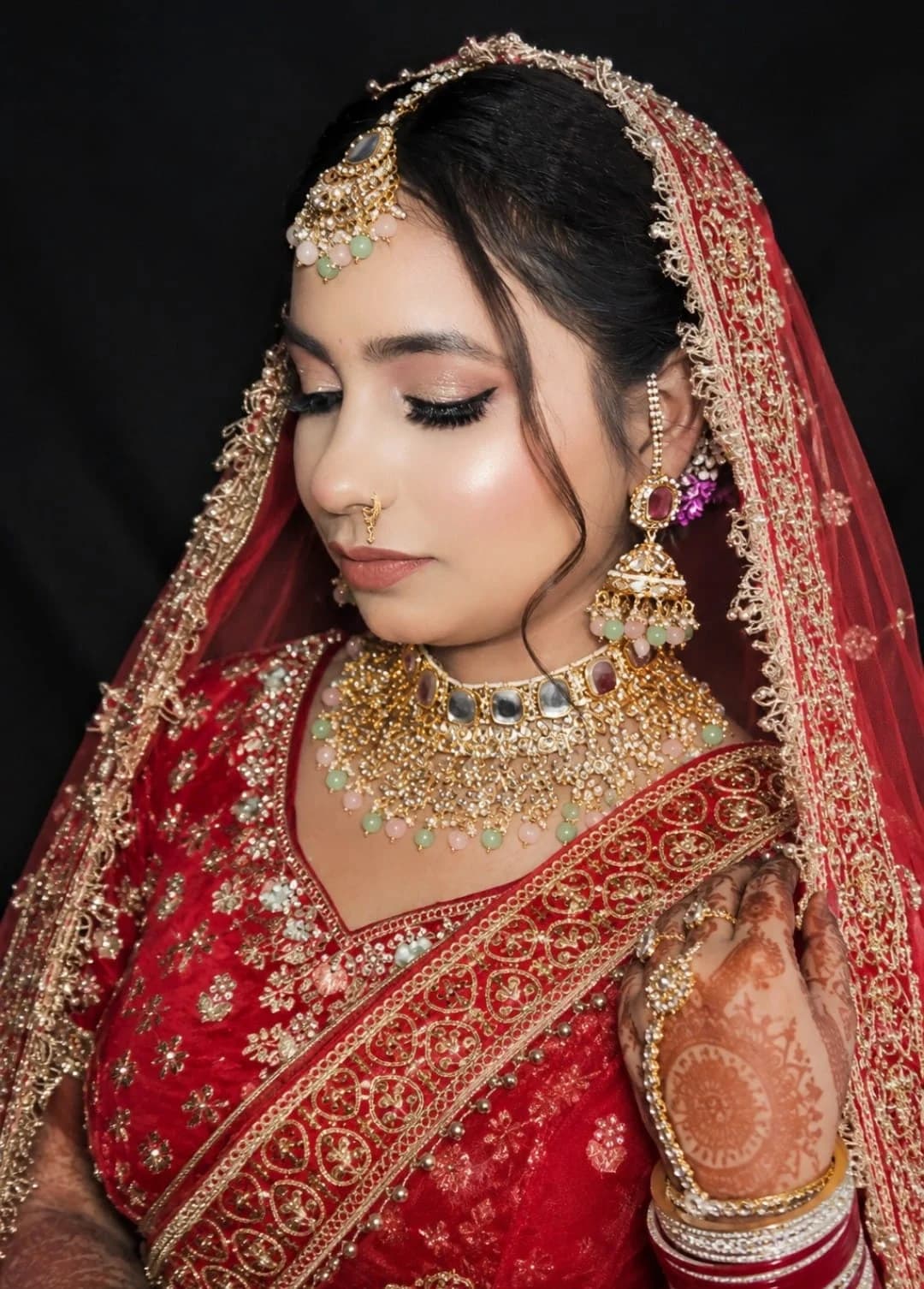 Red bridal look with a luminous base, winged liner and layered kundan jewellery