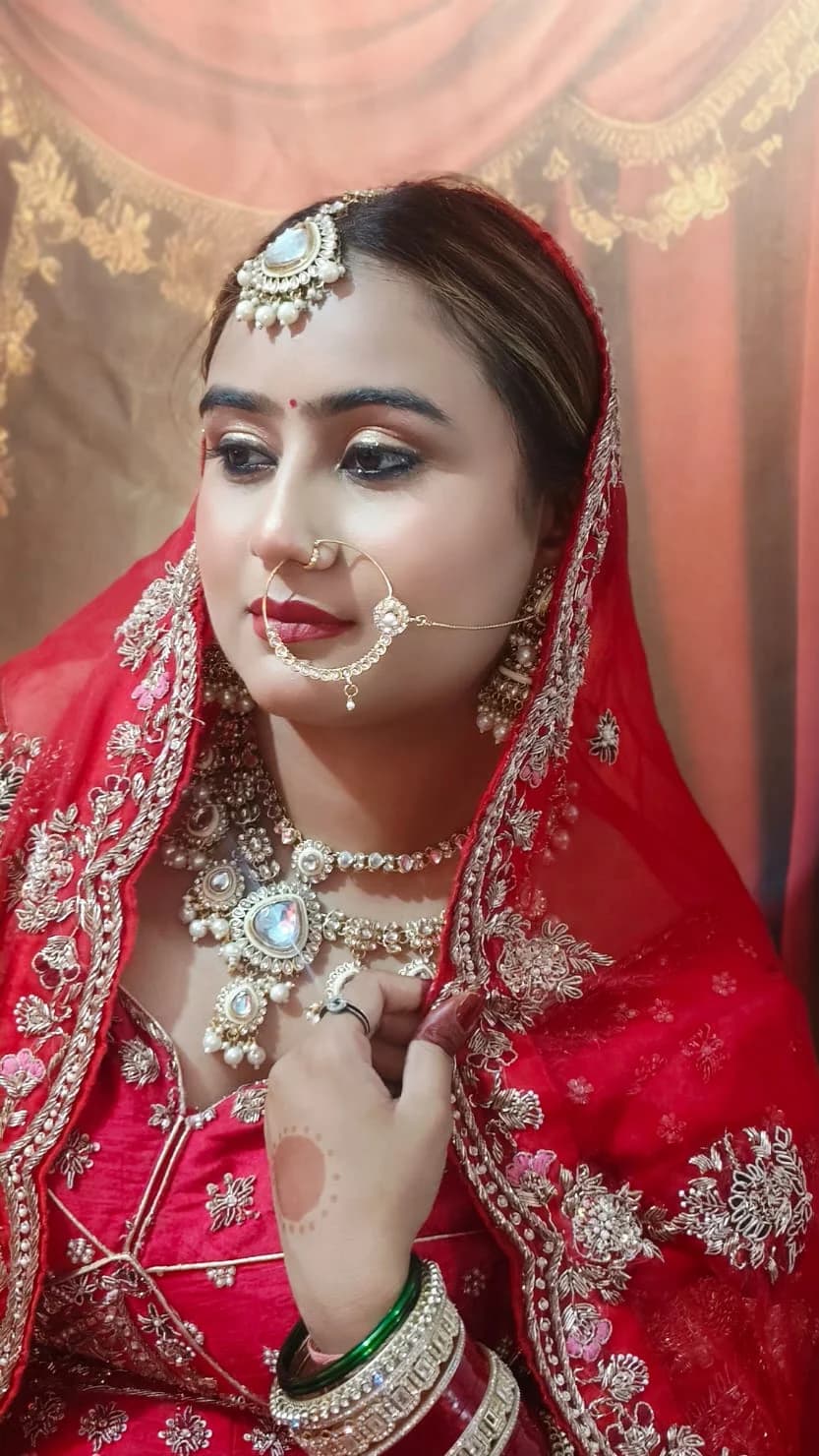 Red bridal look with a chain nath and mirrored kundan choker, with full henna